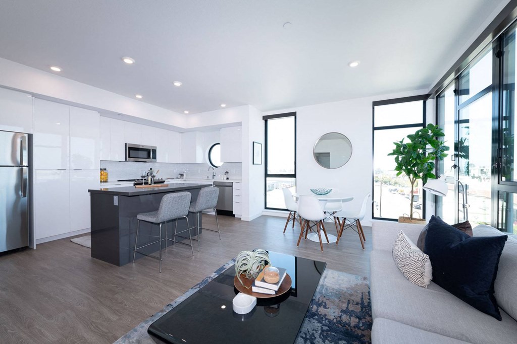 a kitchen and living room with white walls and hardwood floors