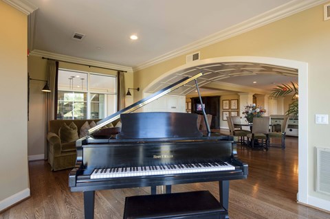 A grand piano sits in a living room with a couch and chairs.