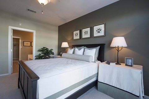 A bedroom with a large bed and two lamps.