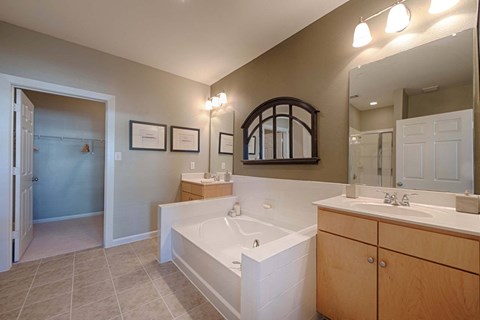A bathroom with a tub, sink, and mirror.