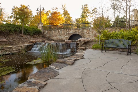 A small waterfall in a park with a bench.