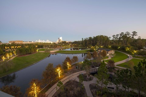 A beautiful landscape with a lake, trees, and a building in the distance.