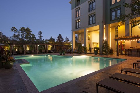 A large swimming pool in front of a building at night.