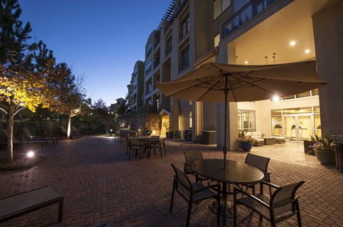 A patio with a table and chairs is lit up at night.