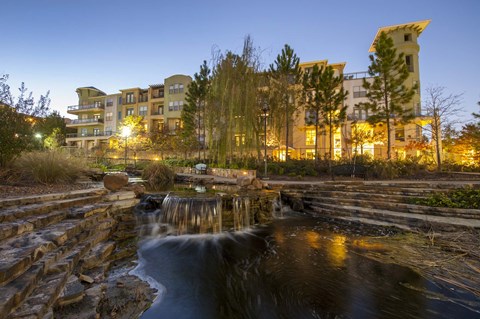 A waterfall flows into a pond in front of a building.