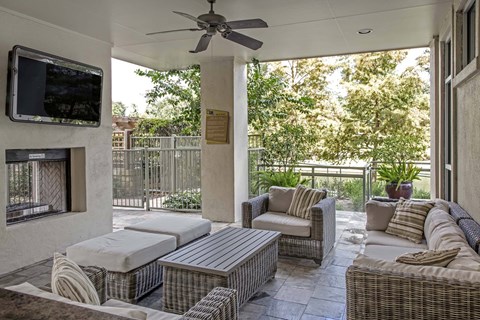 A patio with a wicker sofa set and a television mounted on the wall.