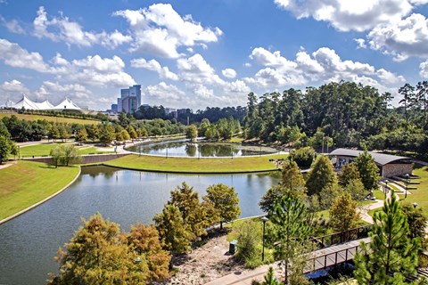 A serene landscape with a lake, trees, and a bridge.
