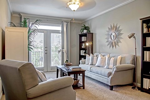 A living room with a grey couch, a chair, a table, and a mirror on the wall.