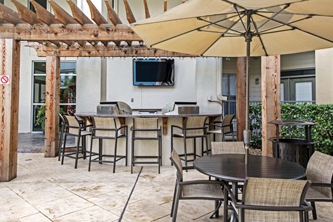 A patio with a table, chairs, and a TV mounted on the wall.