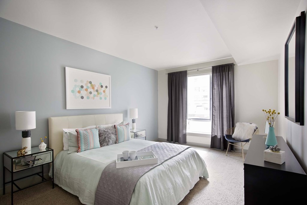 A bedroom with a large bed and a painting on the wall.