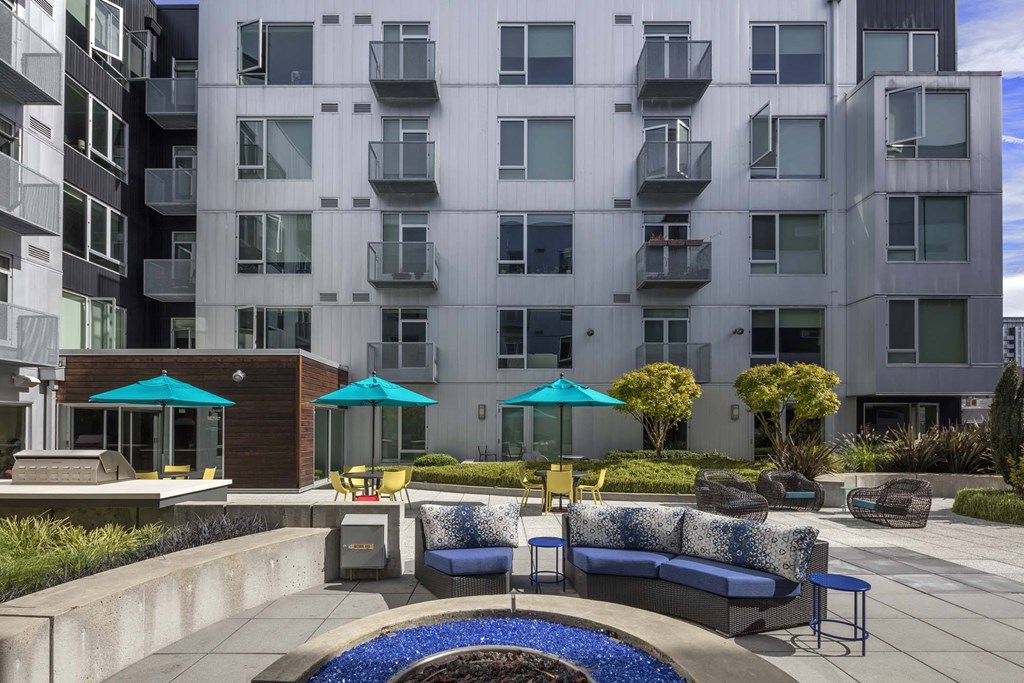 A modern apartment complex with a pool and seating area.