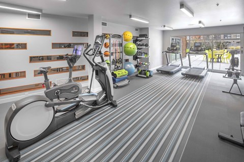 A gym with a treadmill, elliptical trainer, and other exercise equipment.