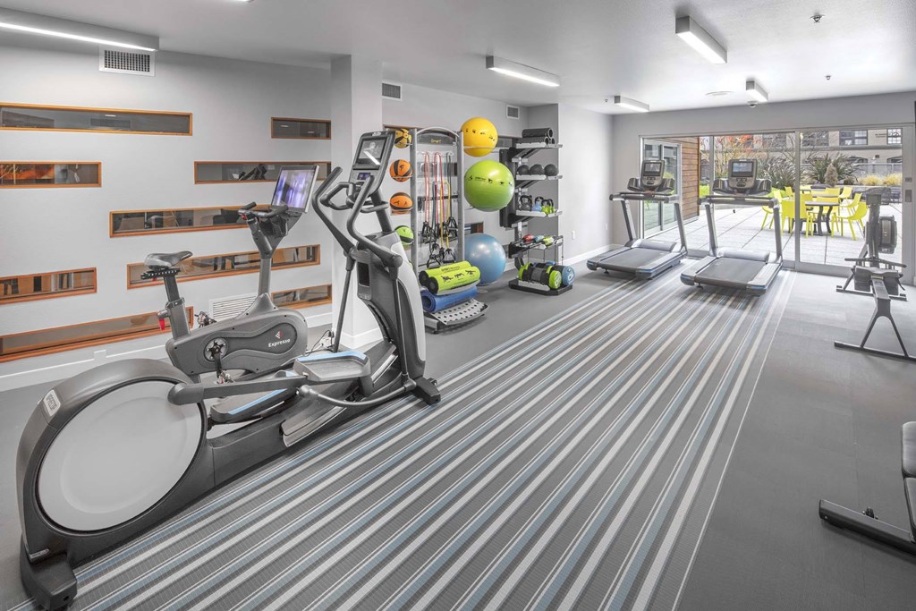 A gym with a treadmill, elliptical trainer, and other exercise equipment.