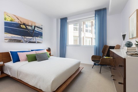 A bedroom with a large bed and a painting of a boat on the wall.