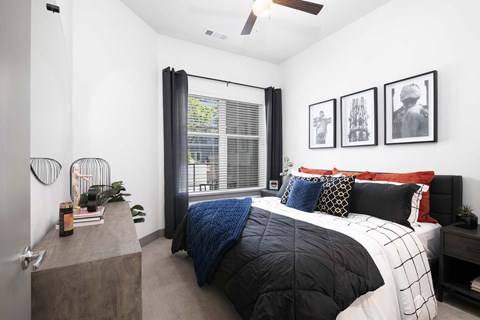 A bedroom with a bed, a nightstand, and a window with curtains.