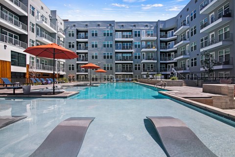 A large swimming pool with a metal diving board in the middle of it.