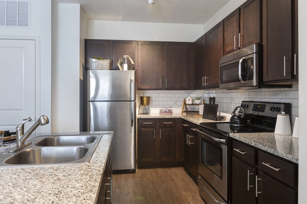 A kitchen with dark wood cabinets and stainless steel appliances.