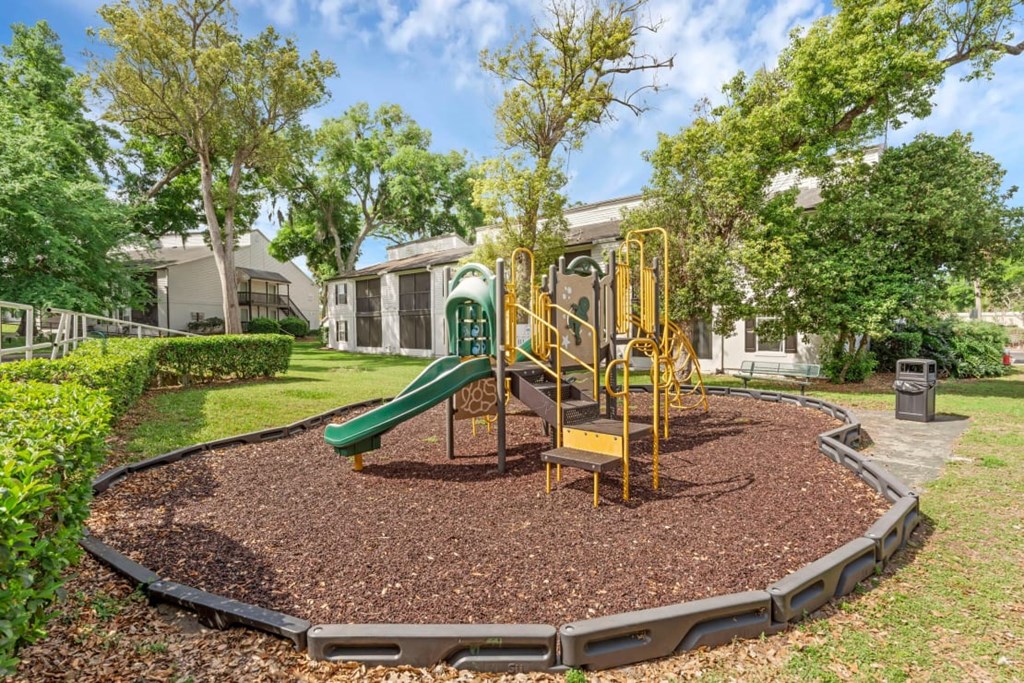 A playground with a green slide and yellow swings.