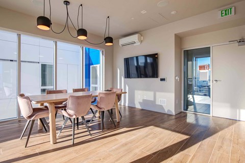 A conference room with a long table and chairs, a television, and a view of the outside.