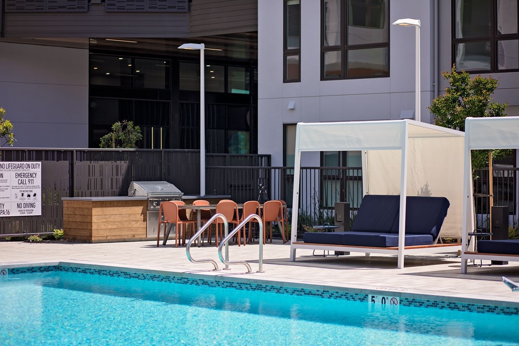 A pool with a blue water and a sunbed.