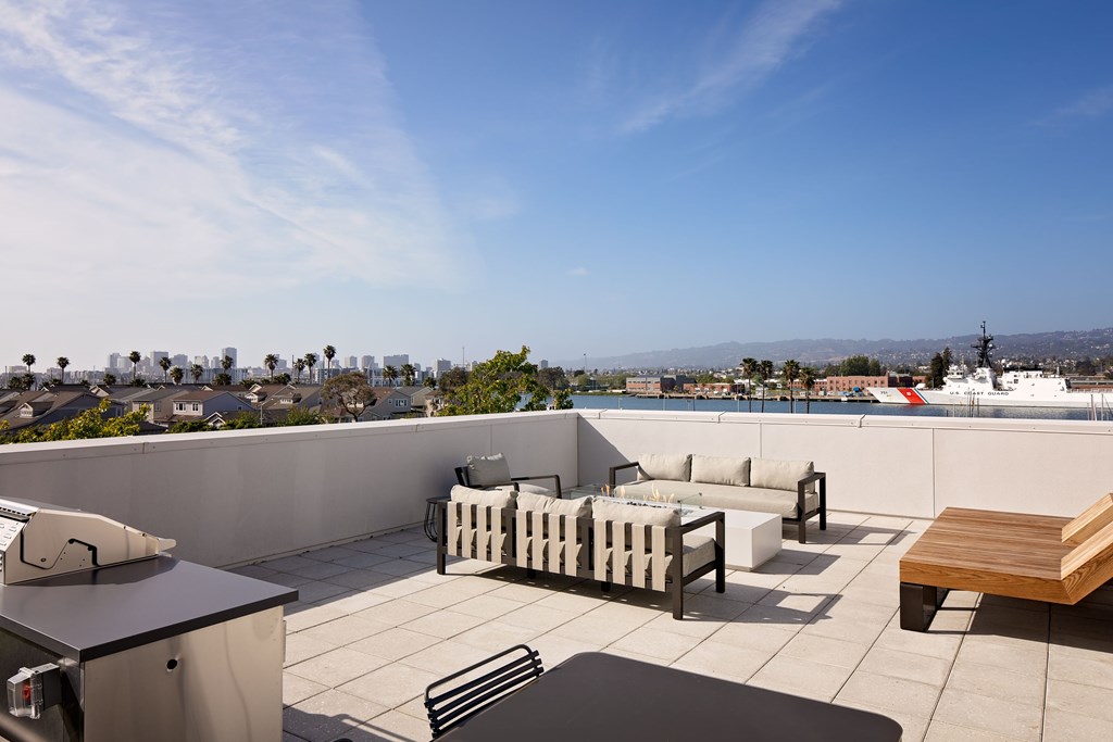 A rooftop patio with a table and chairs overlooking a city.