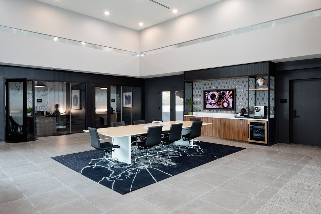 A conference room with a white table surrounded by black chairs.