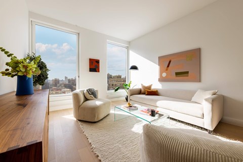 A living room with a white couch, a chair, a coffee table, and a painting on the wall.
