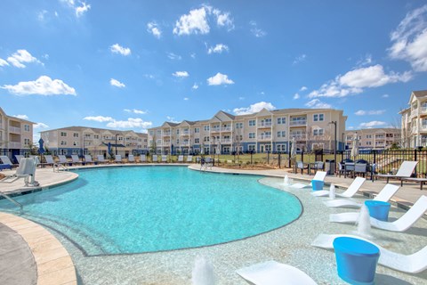 A large swimming pool surrounded by white lounge chairs.