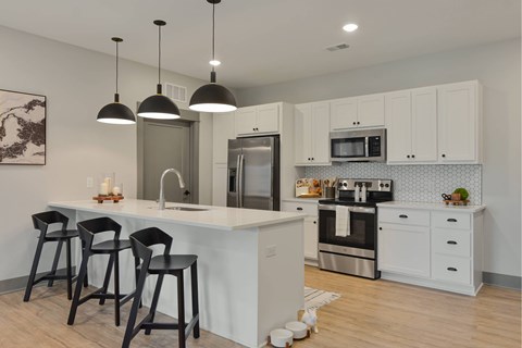 A kitchen with white cabinets and a white island with black barstools.