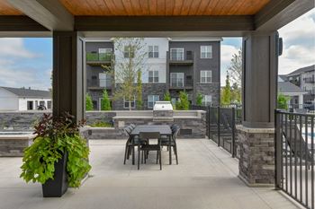 A patio with a table and chairs is surrounded by a black fence.