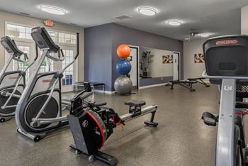A gym with a variety of equipment including treadmills, exercise balls, and weight machines.