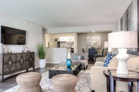 A modern living room with a dark wood cabinet, a white sofa, and a coffee table with a blue vase on it.