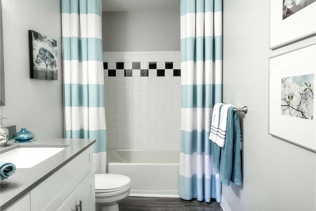 A bathroom with a toilet, sink, and striped shower curtain.