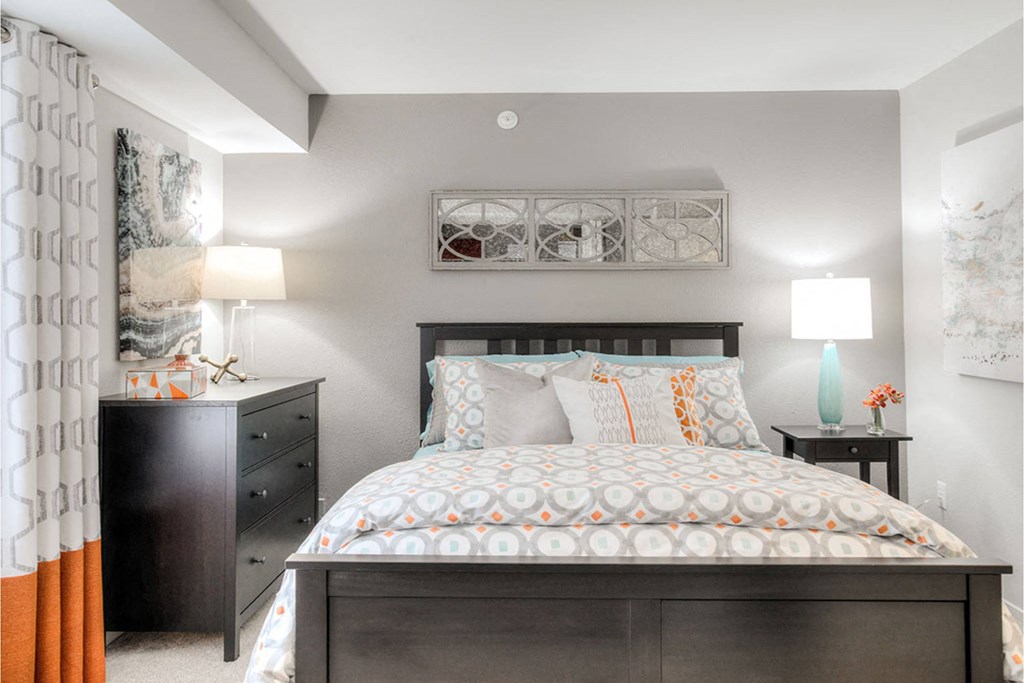 A bedroom with a large bed and a nightstand with a lamp.