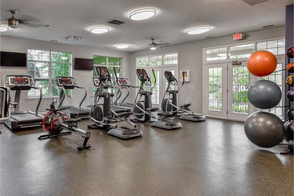 A gym with treadmills, elliptical machines, and exercise balls.