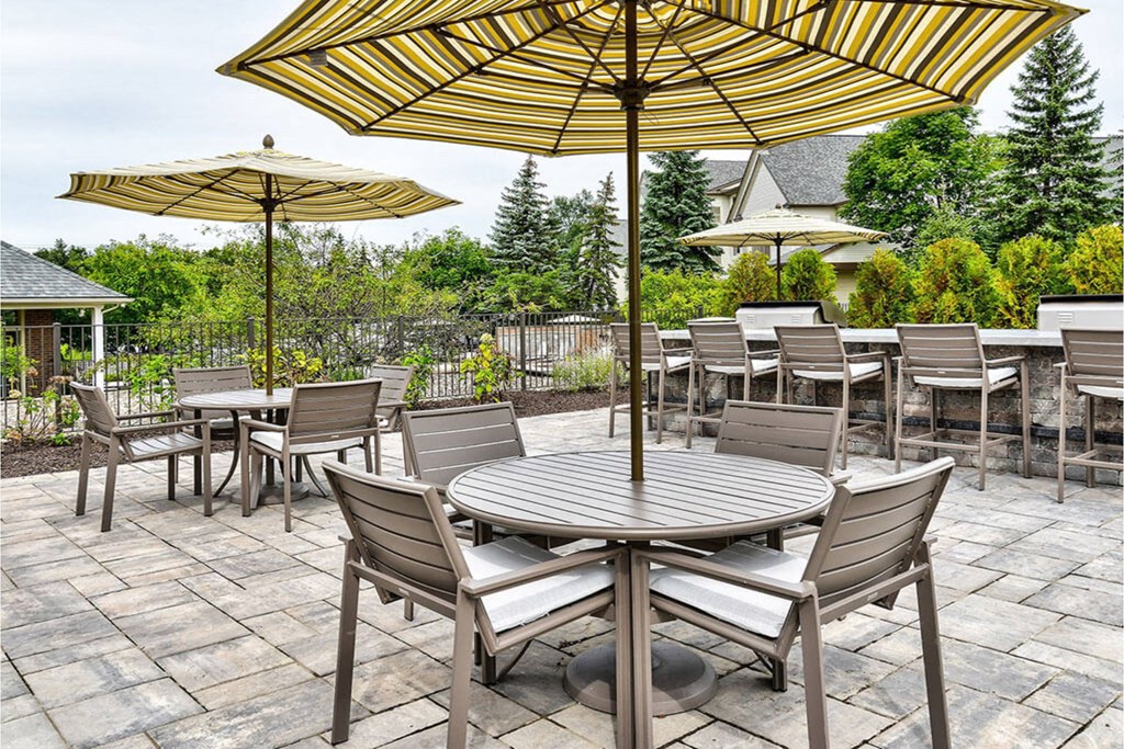 A patio with a table and chairs under umbrellas.