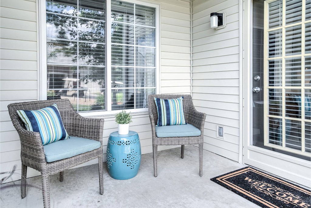 Two chairs and a table on a porch.
