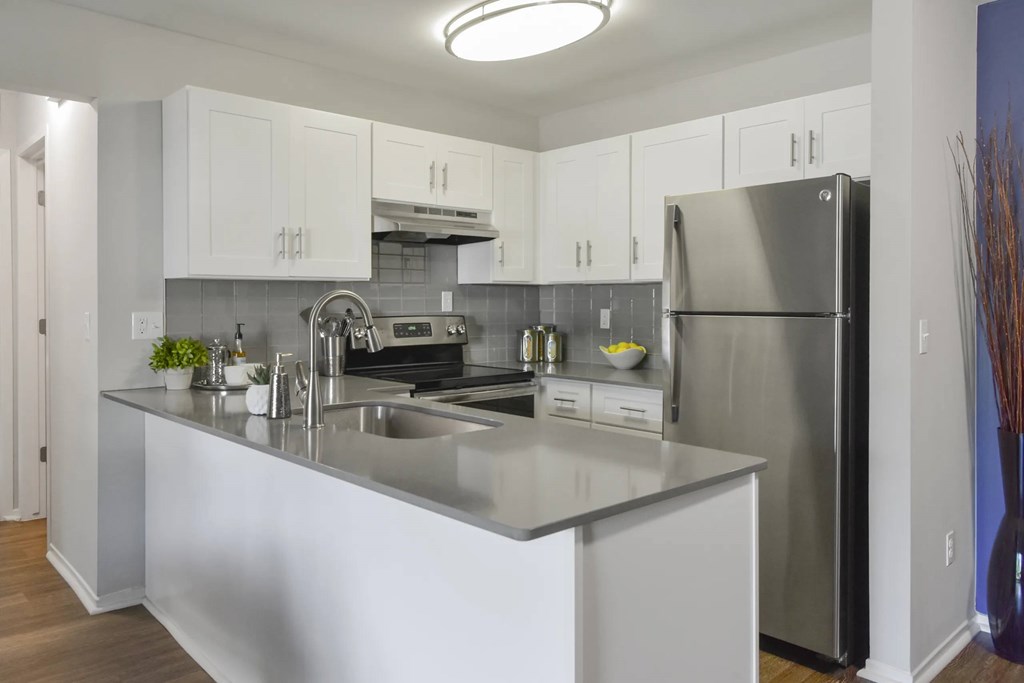 A modern kitchen with a stainless steel refrigerator and white cabinets.