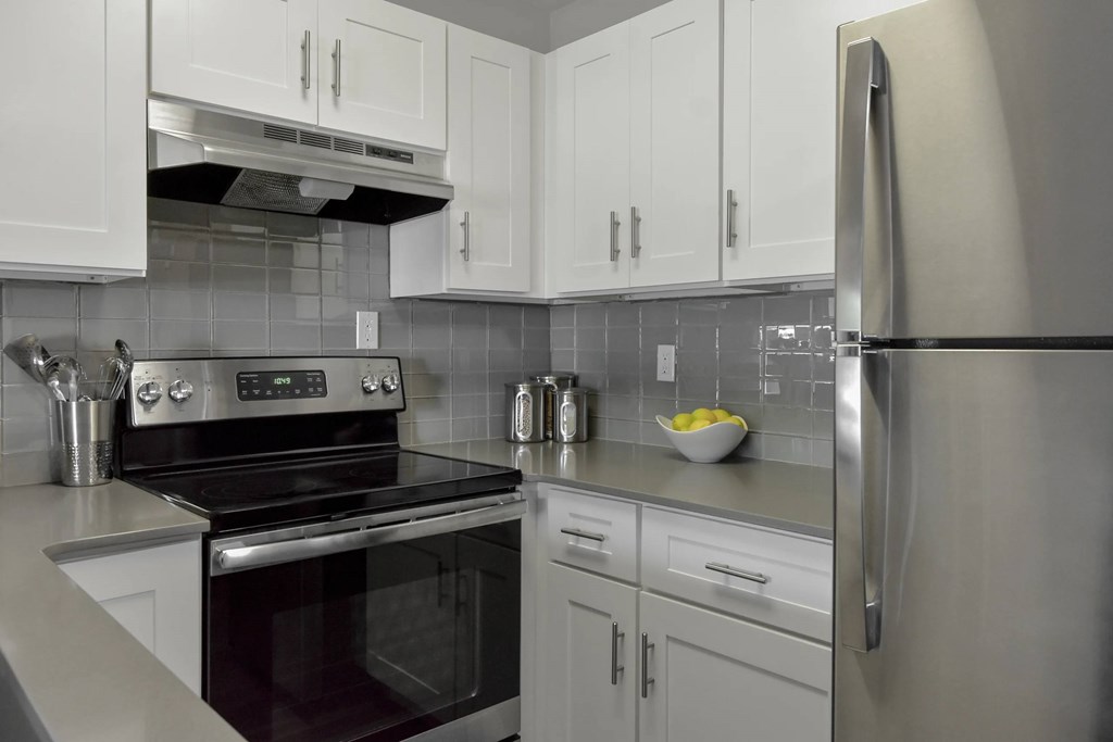 A modern kitchen with a stove, refrigerator, and cabinets.