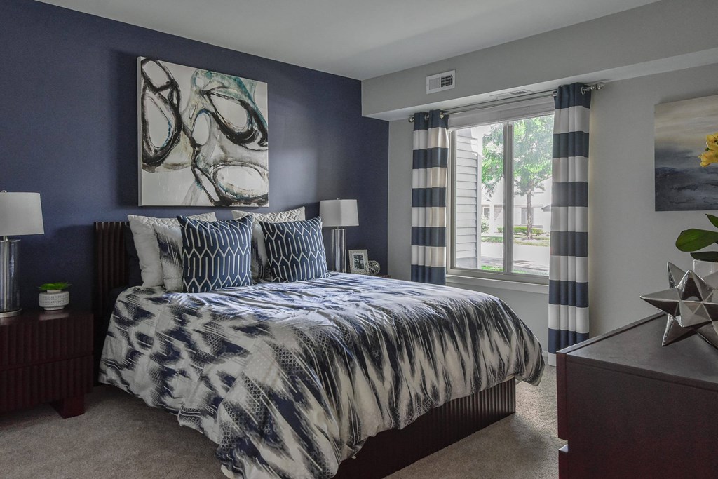 A bedroom with a large bed and a painting on the wall.