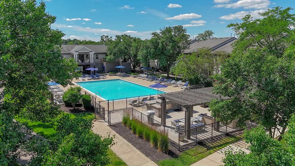 A pool surrounded by trees and a fence.
