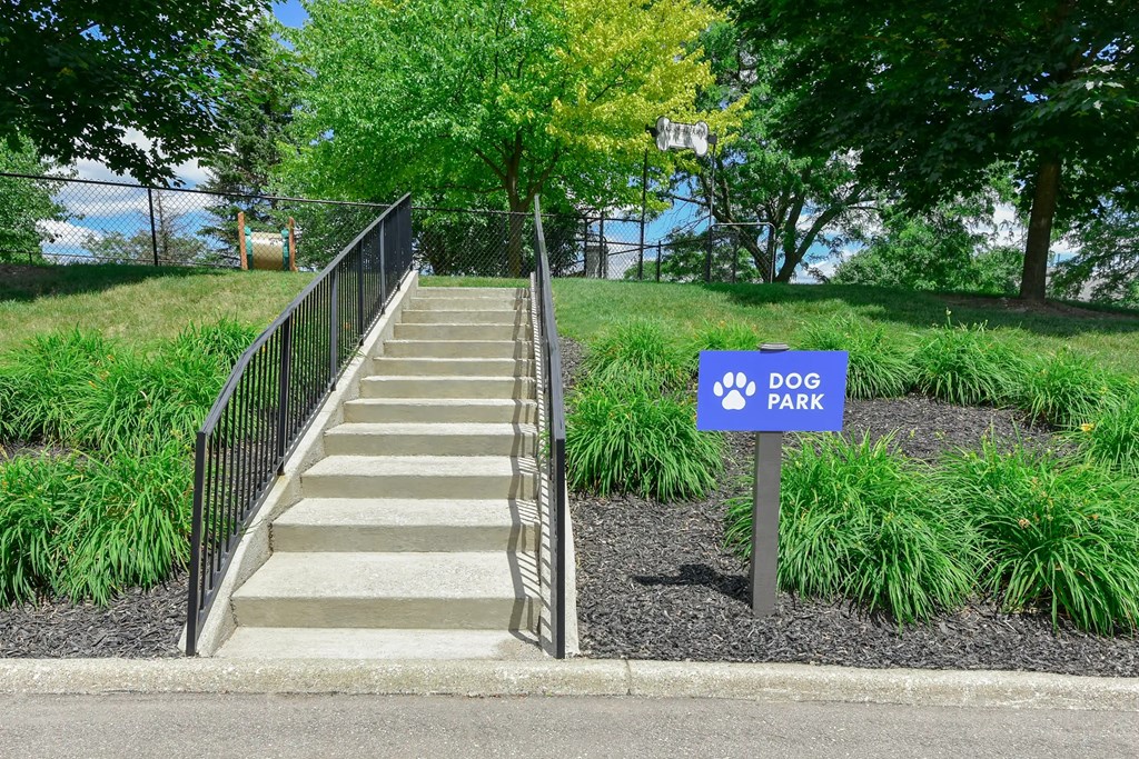 A set of stairs leads to a park with a sign on the right.