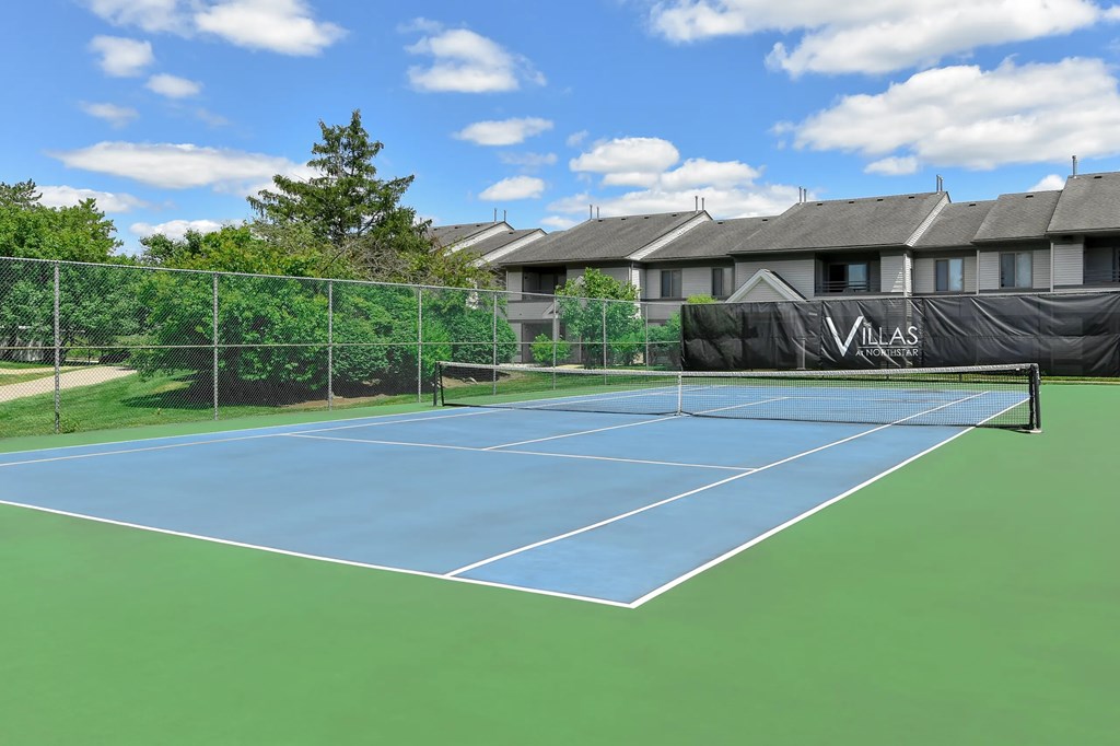 A tennis court with a net and a sign that says "VILLAS".