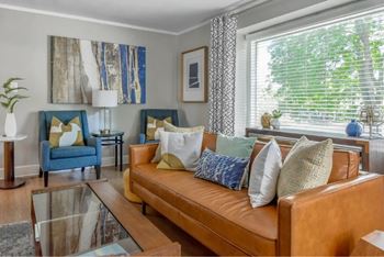 A living room with a brown leather couch and a blue chair.