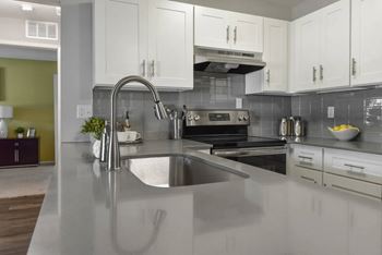 A modern kitchen with a stainless steel sink and white cabinets.