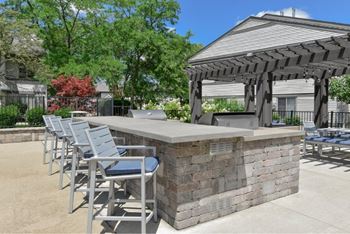 A patio with a bar and chairs under a pergola.