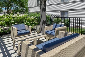 A patio with a wicker chair and a blue cushion.