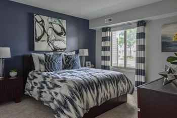 A bedroom with a large bed and a painting on the wall.