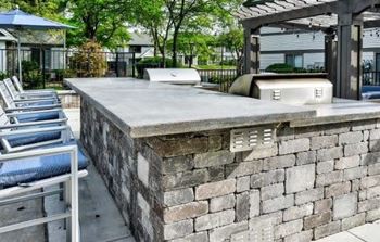 A concrete patio with a stone wall and a bench.