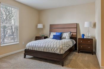 A bedroom with a bed, nightstands, and a carpeted floor.